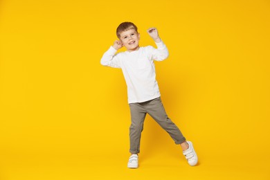 Photo of Happy little boy dancing on orange background