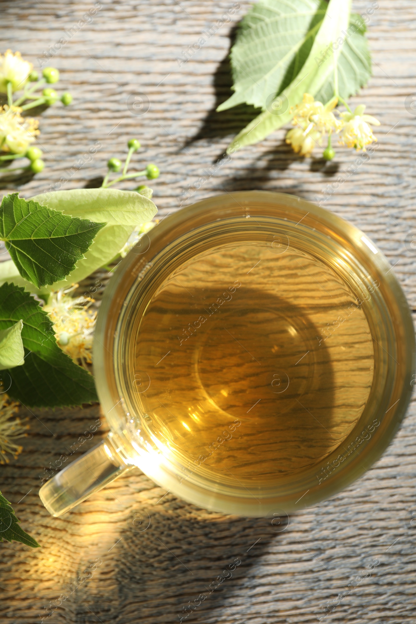 Fresh linden tea in cup and flowers on wooden table, flat lay Photo of Fresh linden tea in cup and flowers on wooden table, flat lay