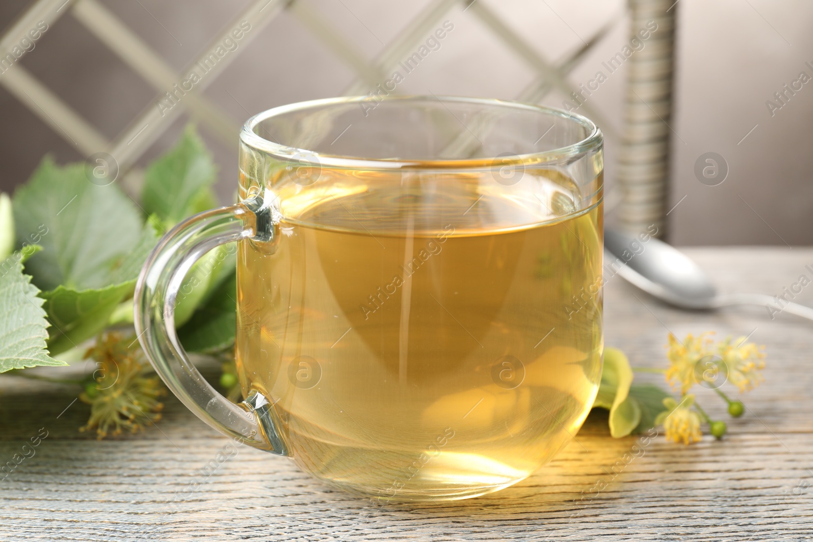 Fresh linden tea in cup and flowers on wooden table, closeup Photo of Fresh linden tea in cup and flowers on wooden table, closeup
