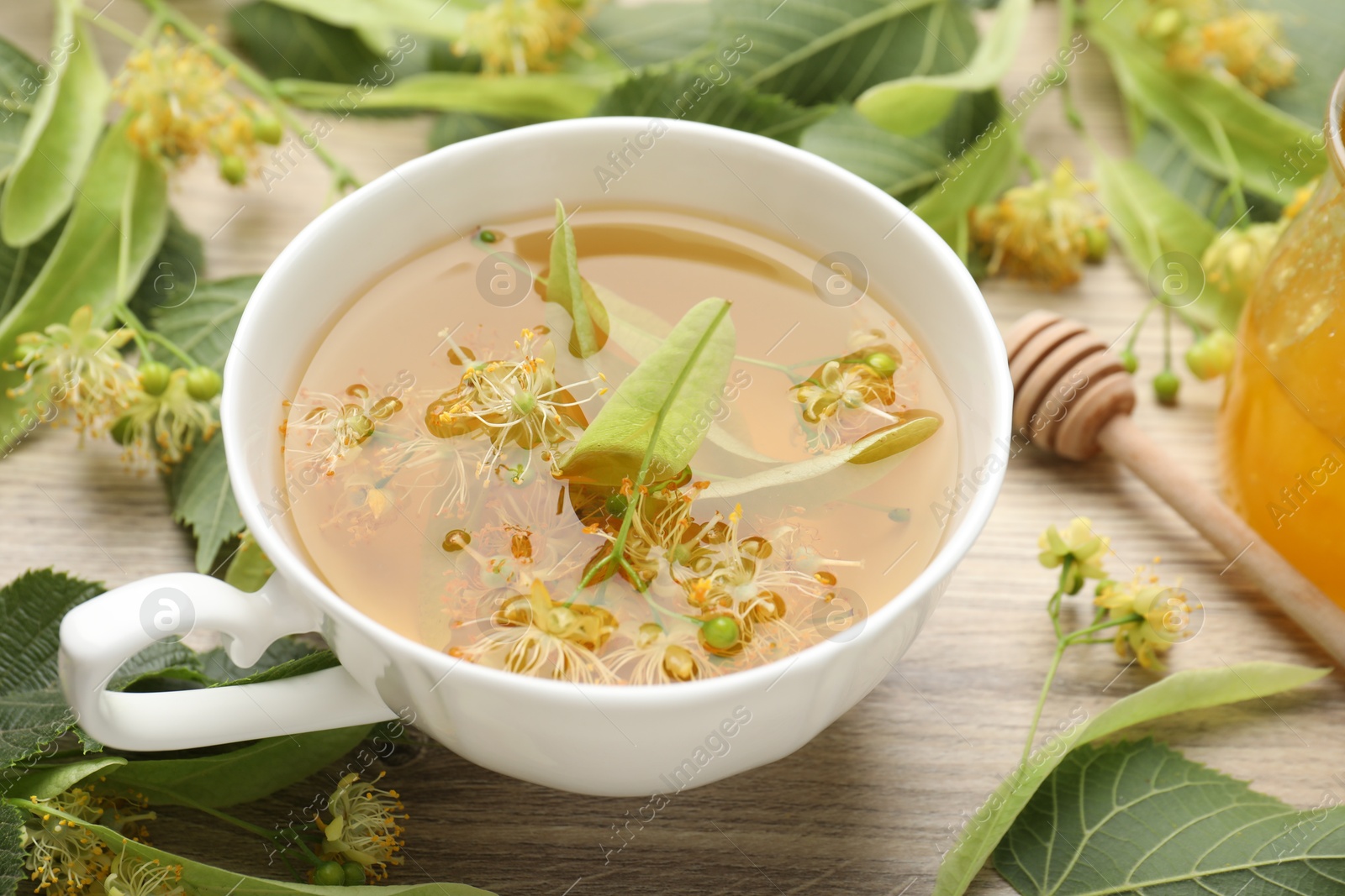Fresh linden tea in cup, honey and flowers on wooden table, closeup Photo of Fresh linden tea in cup, honey and flowers on wooden table, closeup