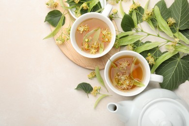Photo of Fresh linden tea in cups, teapot and flowers on white table, flat lay. Space for text