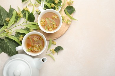 Photo of Fresh linden tea in cups, teapot and flowers on white table, flat lay. Space for text