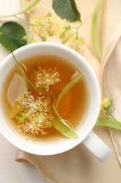 Photo of Fresh linden tea in cup and flowers on white table, flat lay