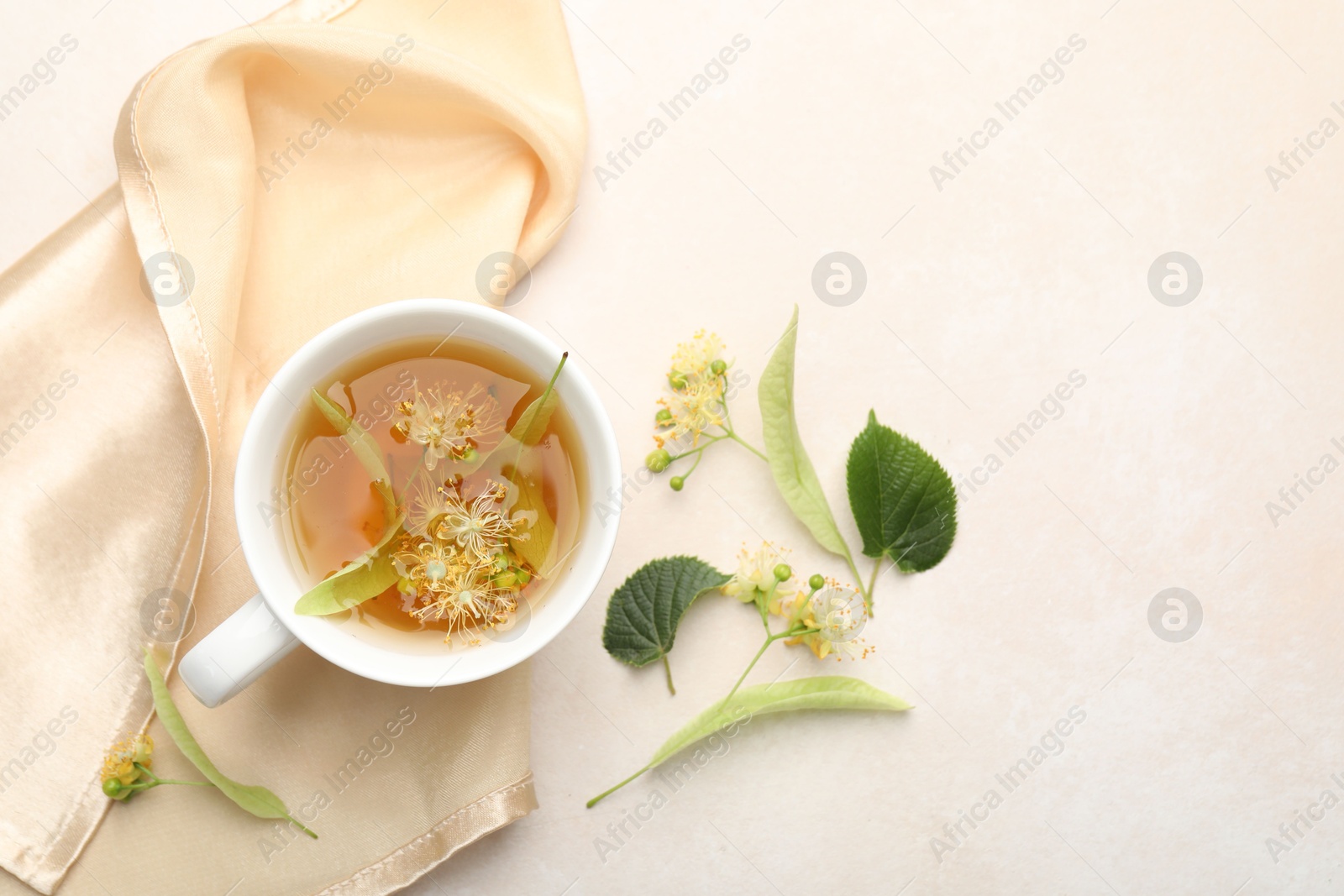 Fresh linden tea in cup and flowers on white table, flat lay. Space for text Photo of Fresh linden tea in cup and flowers on white table, flat lay. Space for text