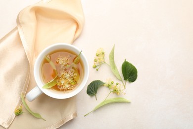 Photo of Fresh linden tea in cup and flowers on white table, flat lay. Space for text