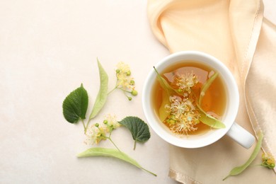 Photo of Fresh linden tea in cup and flowers on white table, flat lay. Space for text