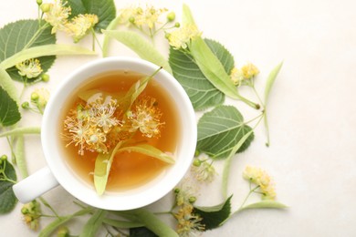 Photo of Fresh linden tea in cup and flowers on white table, flat lay