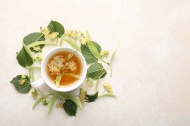 Photo of Fresh linden tea in cup and flowers on white table, flat lay. Space for text
