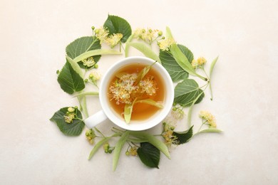 Photo of Fresh linden tea in cup and flowers on white table, flat lay