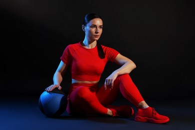 Photo of Woman with medicine ball on black background