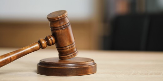 Photo of Judge's gavel on wooden table in office, closeup. Space for text