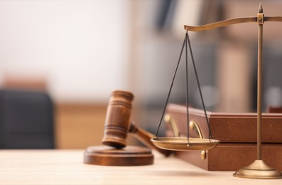 Photo of Judge's gavel, scales and document tray on wooden table in office, closeup. Space for text