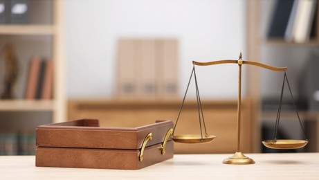 Photo of Scales of justice and document tray on wooden table in office