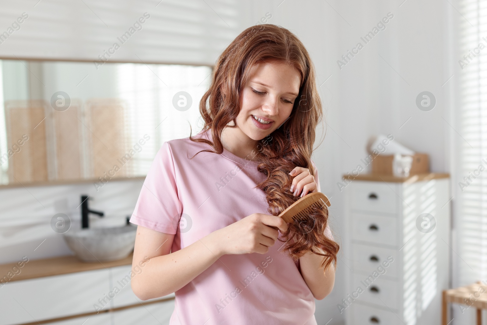 Smiling teenage girl brushing her shiny hair at home Photo of Smiling teenage girl brushing her shiny hair at home