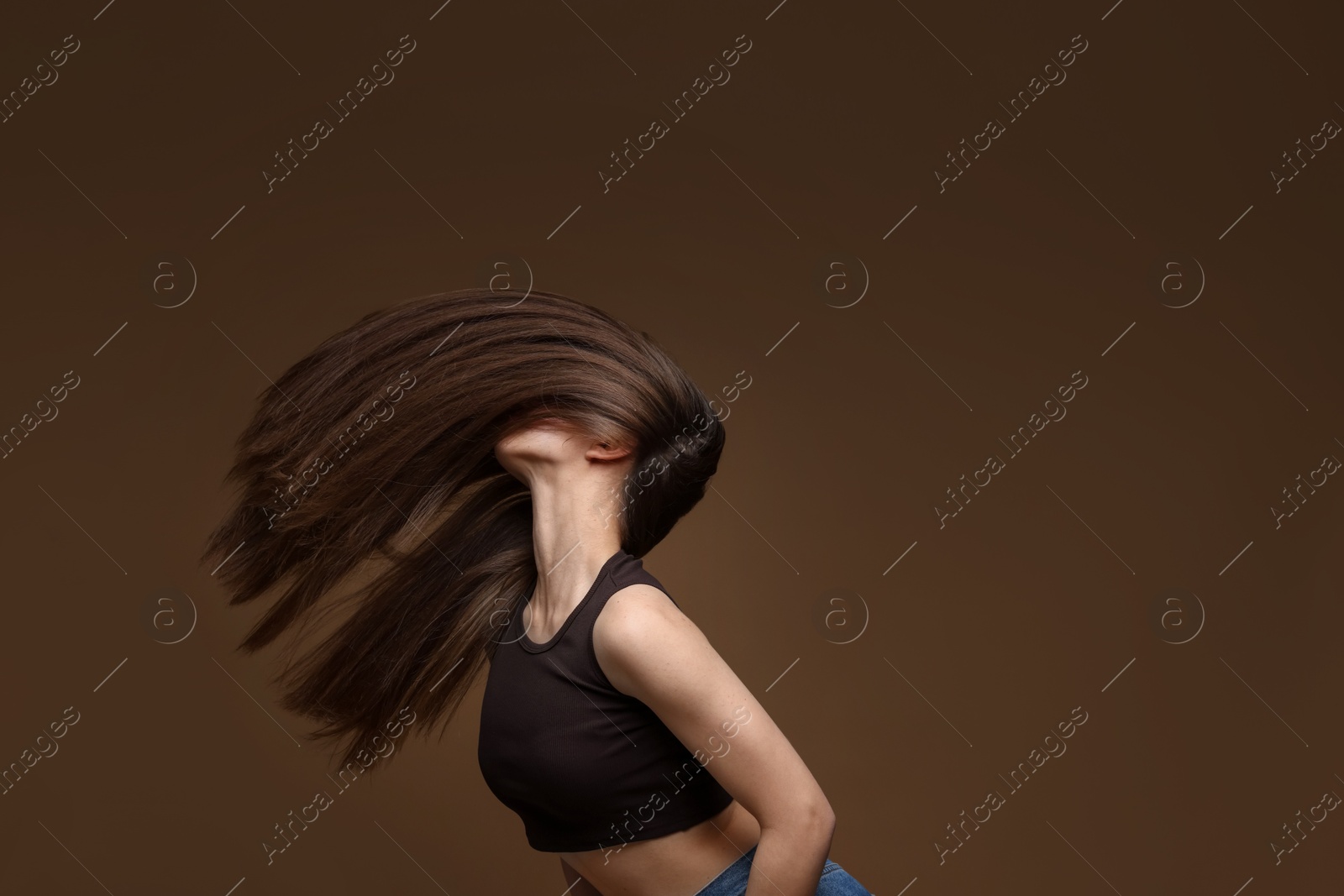 Teenage girl with healthy long hair on brown background Photo of Teenage girl with healthy long hair on brown background
