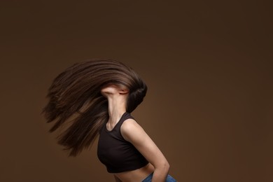 Photo of Teenage girl with healthy long hair on brown background