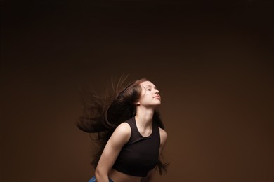 Photo of Teenage girl with healthy long hair on brown background