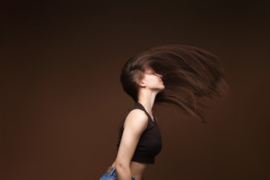 Photo of Teenage girl with healthy long hair on brown background
