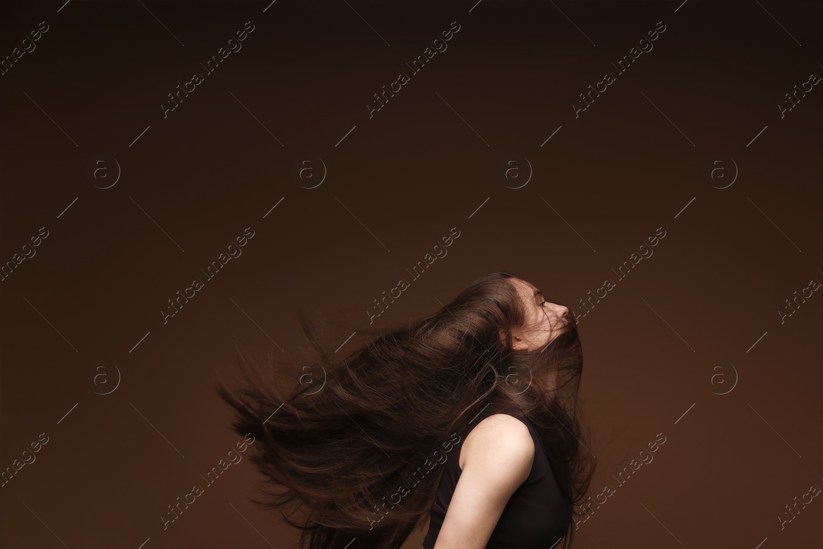 Teenage girl with healthy long hair on brown background Photo of Teenage girl with healthy long hair on brown background