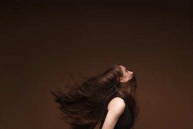 Photo of Teenage girl with healthy long hair on brown background
