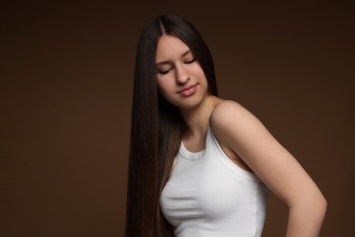 Photo of Beautiful teenage girl with healthy long hair on brown background