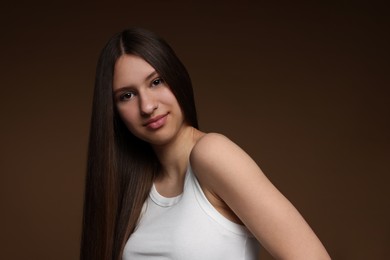 Photo of Portrait of beautiful teenage girl with healthy long hair on brown background