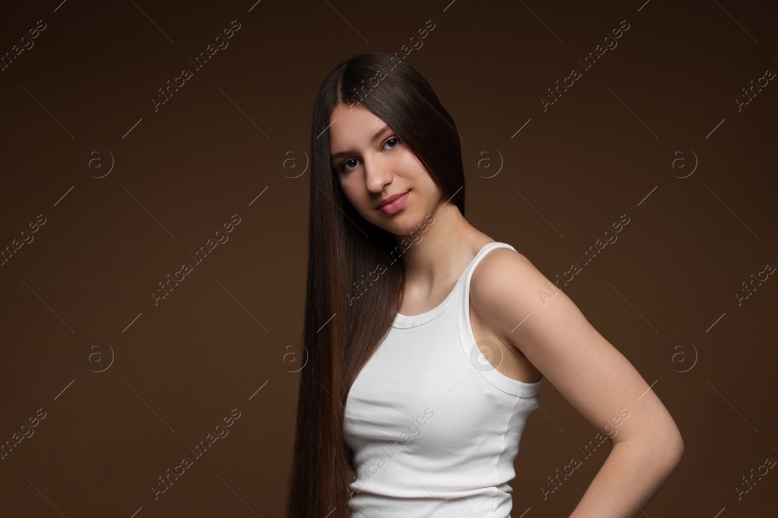 Portrait of beautiful teenage girl with healthy long hair on brown background Photo of Portrait of beautiful teenage girl with healthy long hair on brown background