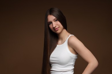 Photo of Portrait of beautiful teenage girl with healthy long hair on brown background