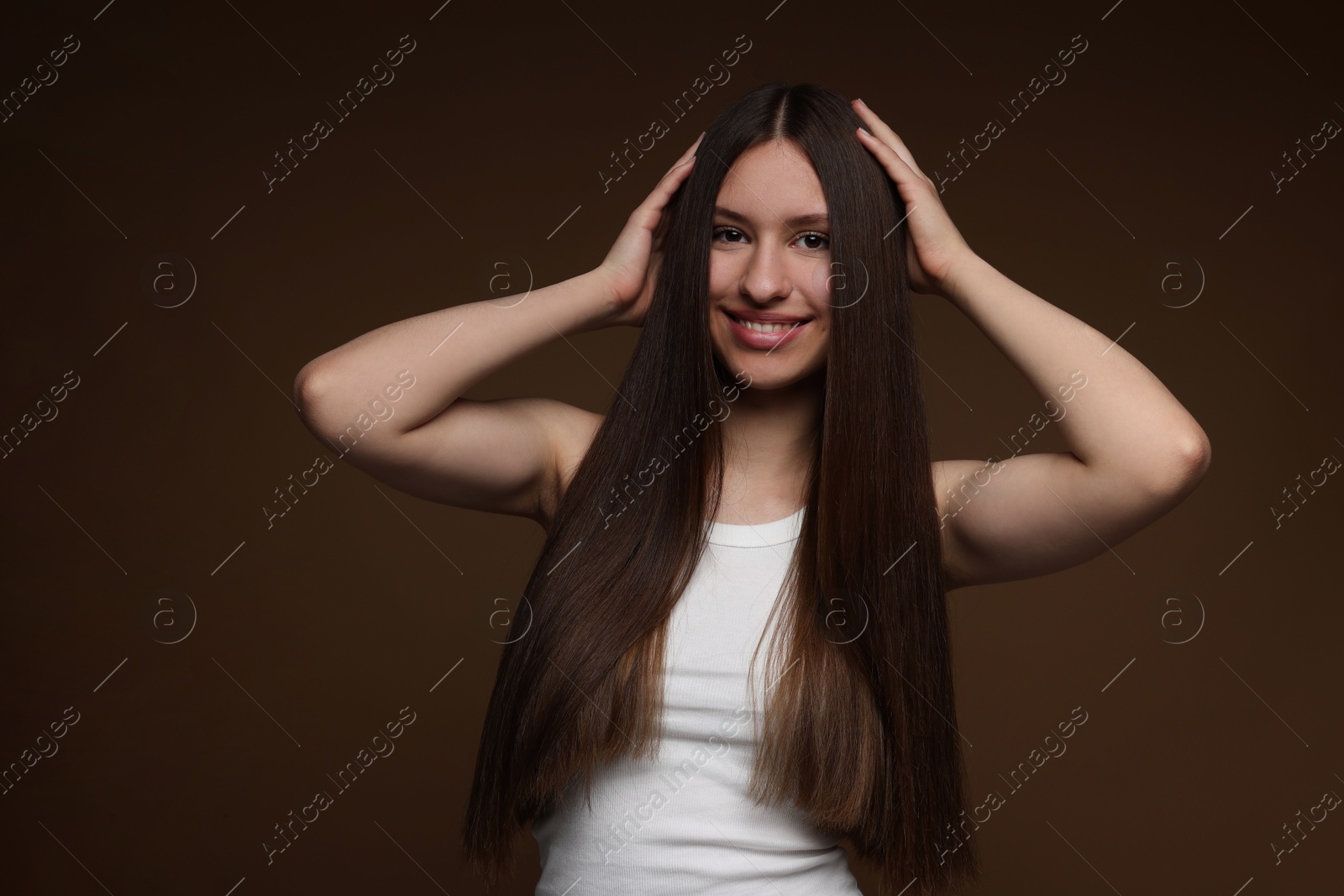 Portrait of smiling teenage girl with healthy long hair on brown background Photo of Portrait of smiling teenage girl with healthy long hair on brown background