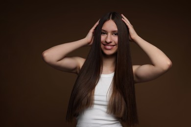 Photo of Portrait of smiling teenage girl with healthy long hair on brown background