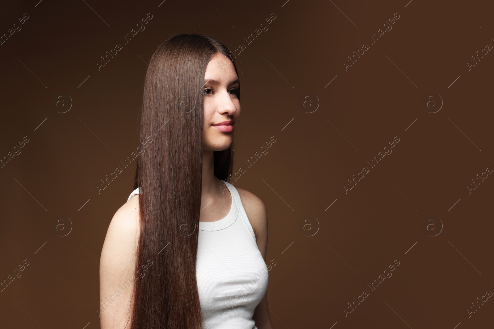 Beautiful teenage girl with healthy long hair on brown background. Space for text Photo of Beautiful teenage girl with healthy long hair on brown background. Space for text