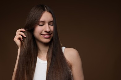 Photo of Smiling teenage girl with healthy long hair on brown background. Space for text