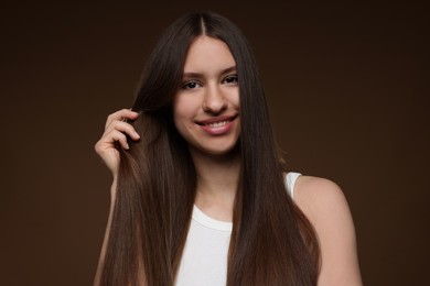 Photo of Portrait of smiling teenage girl with healthy long hair on brown background