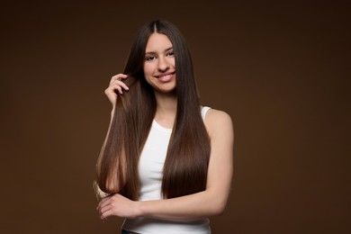 Photo of Portrait of smiling teenage girl with healthy long hair on brown background