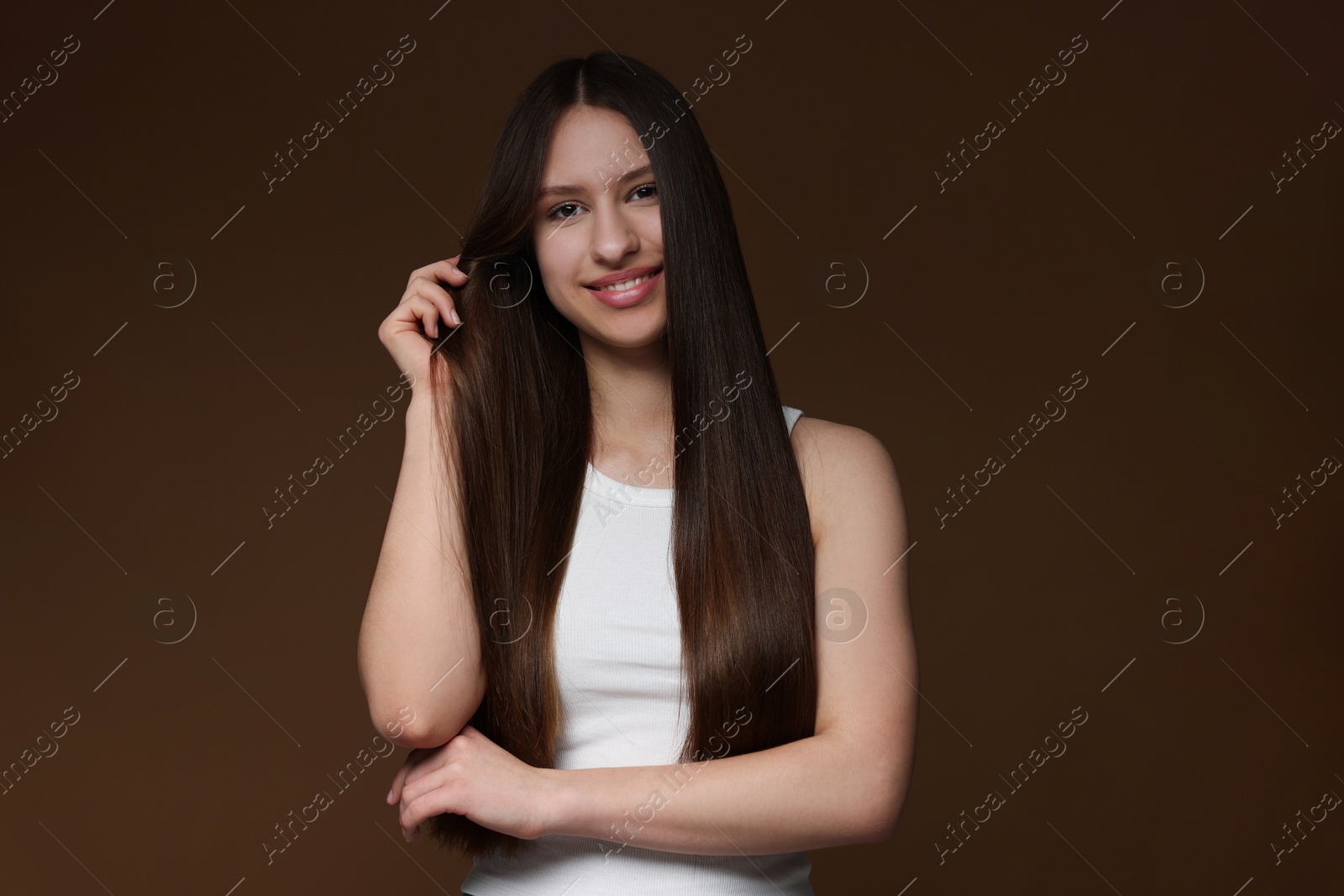 Portrait of smiling teenage girl with healthy long hair on brown background Photo of Portrait of smiling teenage girl with healthy long hair on brown background