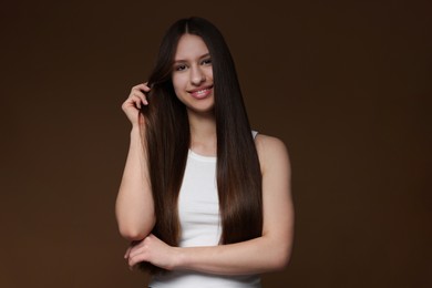 Photo of Portrait of smiling teenage girl with healthy long hair on brown background