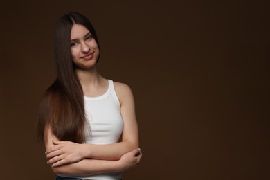 Photo of Portrait of beautiful teenage girl with healthy long hair on brown background. Space for text