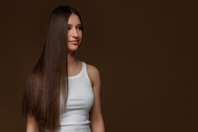 Photo of Beautiful teenage girl with healthy long hair on brown background. Space for text