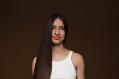 Photo of Portrait of beautiful teenage girl with healthy long hair on brown background