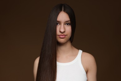 Photo of Portrait of beautiful teenage girl with healthy long hair on brown background