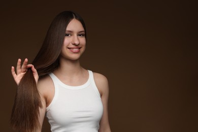 Photo of Portrait of smiling teenage girl with healthy long hair on brown background. Space for text