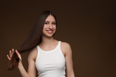 Photo of Portrait of smiling teenage girl with healthy long hair on brown background. Space for text
