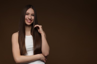 Photo of Portrait of smiling teenage girl with healthy long hair on brown background. Space for text