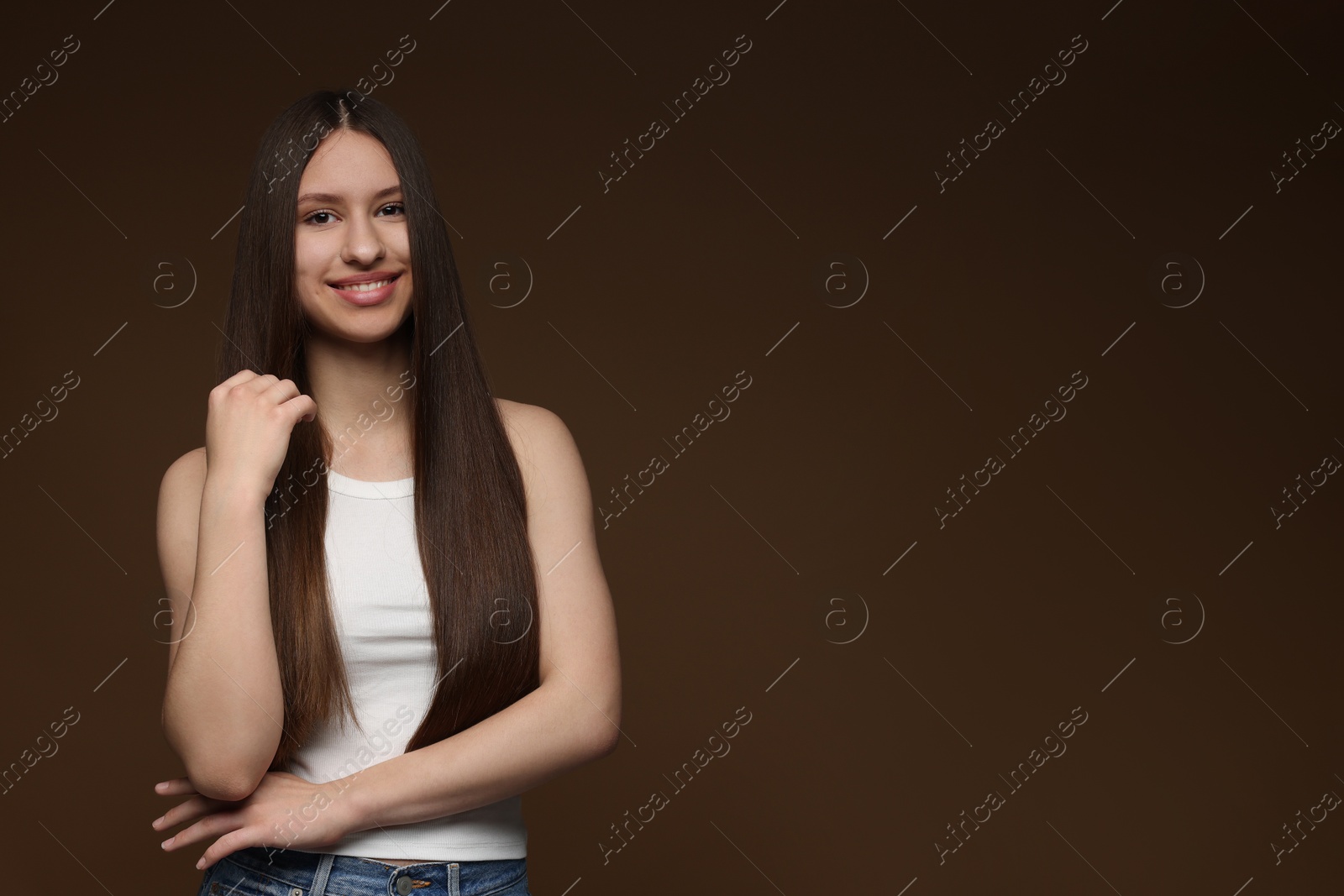 Portrait of smiling teenage girl with healthy long hair on brown background. Space for text Photo of Portrait of smiling teenage girl with healthy long hair on brown background. Space for text