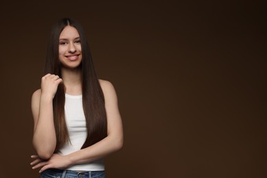 Photo of Portrait of smiling teenage girl with healthy long hair on brown background. Space for text