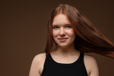 Photo of Portrait of beautiful teenage girl with healthy wavy hair on brown background. Space for text