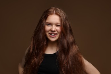 Photo of Portrait of happy teenage girl with healthy wavy hair on brown background