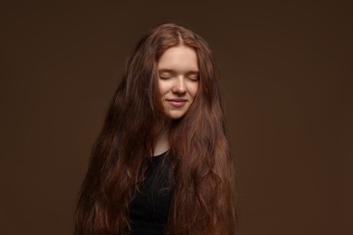 Photo of Beautiful teenage girl with healthy wavy hair on brown background
