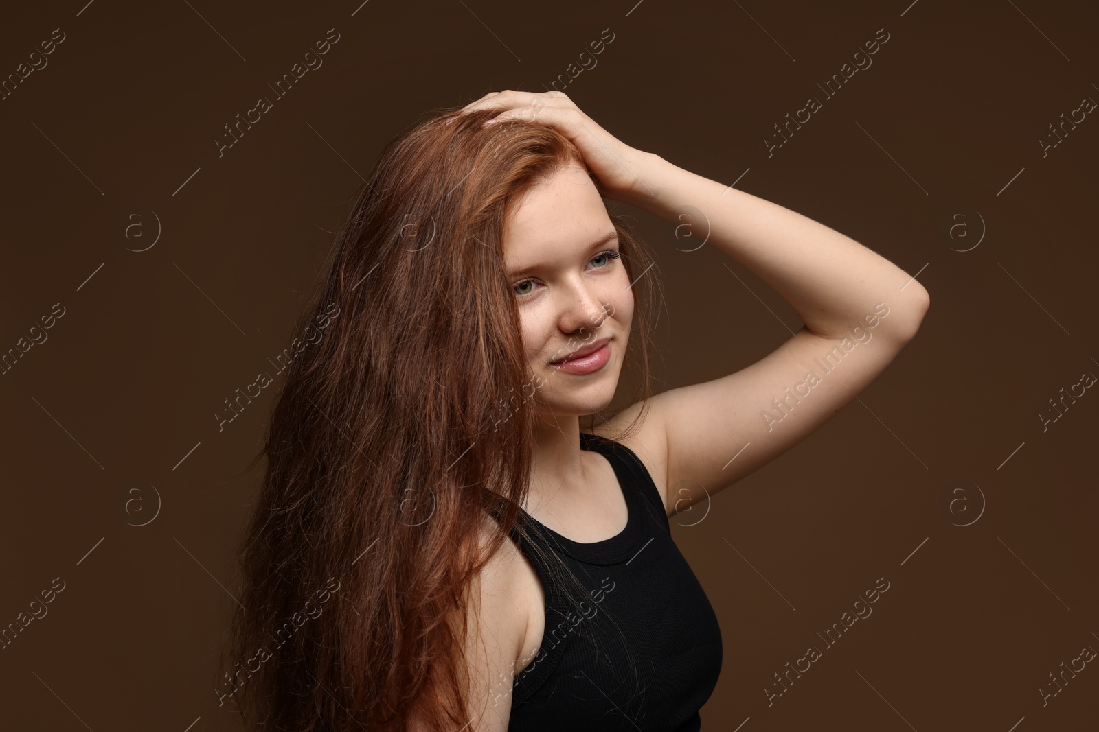 Beautiful teenage girl with healthy wavy hair on brown background Photo of Beautiful teenage girl with healthy wavy hair on brown background