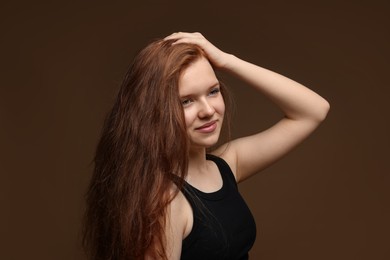 Photo of Beautiful teenage girl with healthy wavy hair on brown background